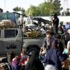 Taliban security personnel look on as Afghan refugees arrive at the Islam Qala border crossing between Afghanistan and Iran