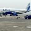 Ground staff walk past an IndiGo airlines aircraft taxiing in the apron at the Netaji Subhash Chandra Bose International Airport in Kolkata in February 2024