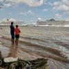 People on a beach along the Guama River watch cruise ships docked at the Port of Outeiro, which will host delegations attending the COP30 UN Climate Change Conference in Belem, Para state, Brazil, on November 6, 2025