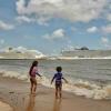 Children bathe on a beach along the Guamá River with cruise ships seen in the background docked at the Port of Outeiro