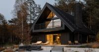 dark timber A&A house reinterprets traditional barn form within polish pine forest