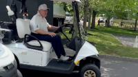 Donald Trump sports huge smile as he rides golf cart at course where ex-wife is buried